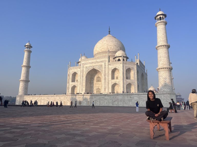 Personne posant devant le Taj Mahal à Agra, avec le monument en marbre blanc en arrière-plan.